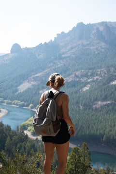 Chica haciendo trekking en piedra de monta&ntilde;a frente a bosque de pinos