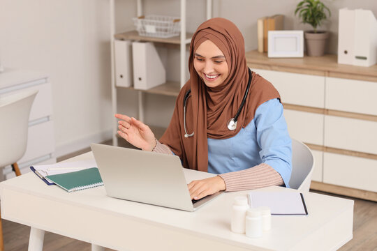 Female Muslim doctor in hijab working with laptop at hospital
