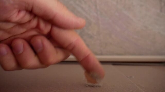 A male hand runs his finger over a dusty surface to show how dirty it is