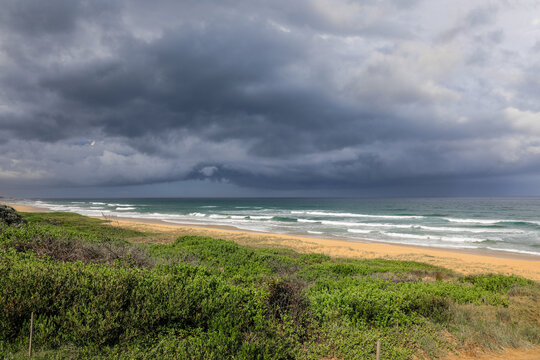 Dark stormy clouds forming over North Beach in Mylestom, New South Wales, Australia. Dramatic coastal scene showing approaching weather over ocean and shoreline.