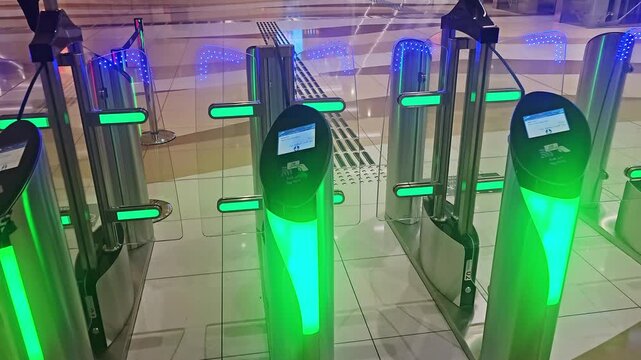 Dubai, Uae - 23rd April 2026 :​ A close-up of a hand tapping a Nol card on a smart metro gate reader with green lights, granting access to the Dubai Metro station platform.