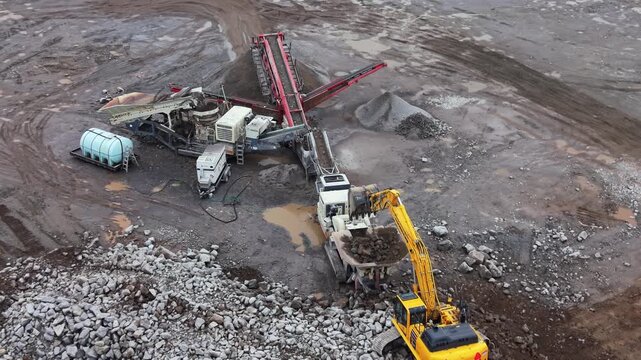 Aerial drone shot of heavy vibrating screen stone crusher crushing rocks in a quarry in Halifax region, Nova Scotia. Mobile equipment for mineral processing and construction materials production 4K.