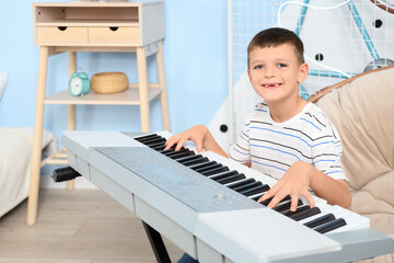 Cute little boy playing synthesizer in bedroom © Pixel-Shot