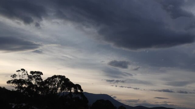 timelapse of soft dusk light over the mountains with thick clouds eucalyptus trees and controlled burns smoke shot in Tasmania