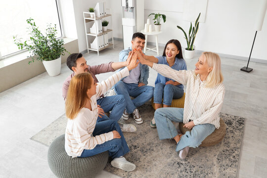 People on poufs giving each other high-five at group therapy session