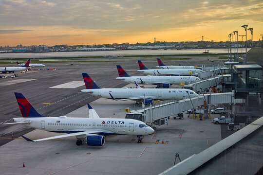 Row of Delta Air Lines aircraft parked at terminal gates at airport during sunrise