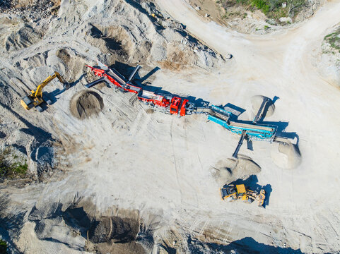 Aerial view of a mobile crushing plant and heavy machinery operating in a limestone quarry with piles of gravel and dirt tracks Indianapolis, Indiana, United States.