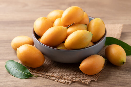 Fresh Marian plum (Mayongchid) in a bowl on wooden background, Thai tropical fruit in summer season