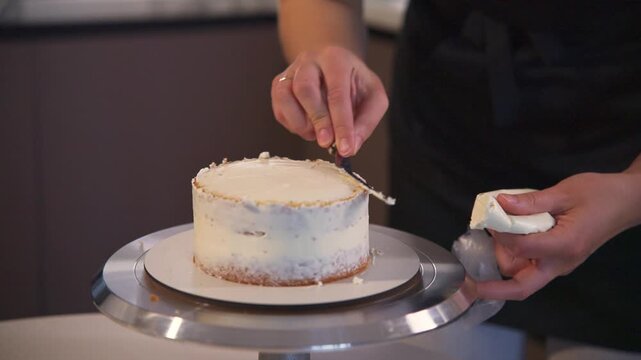 Hands smooth frosting with precision. Careful touch ensures even finish on each layer. Professional baker focuses on perfect texture. Ideal for food, baking, or culinary content