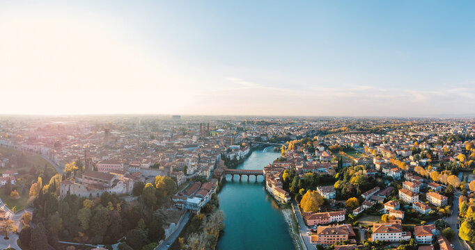 Aerial view of the historic town of Bassano del Grappa with the Brenta River and the iconic Ponte Vecchio bridge under a clear sky Bassano del Grappa, Veneto, Italy.
