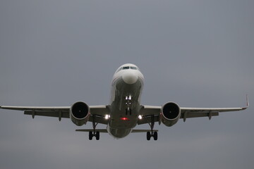 Naklejka premium A commercial passenger airplane approaches for landing in cloudy sky.