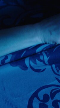 Hand reaching for a smartphone alarm in bed at 5:00 AM, representing waking up, morning routine, and sleep interruption.