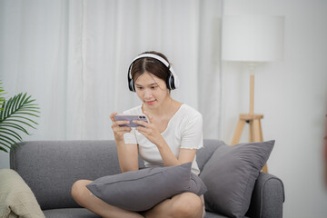 Fototapeta premium Asian woman playing game on mobile phone. gamer girl playing video games holding Smartphone&nbsp;working mobile devices. cell telephone technology e-commerce concept