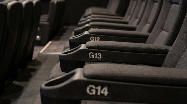 Rows of numbered cinema seats in a dark theater environment  