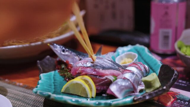Chopsticks Grab Raw Sama "Pacific Saury" Sashimi in Japanese Restaurant