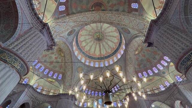 Cinematic 4K shot looking up at the magnificent ceiling of the Blue Mosque in Istanbul. Showcases the intricate Ottoman patterns, stunning stained glass windows, and massive chandeliers.