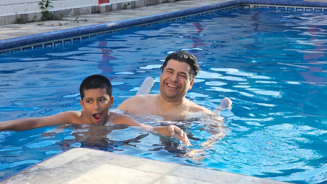 Divorced single dad and his 11-year-old Latino son play in the pool and teach him to swim during their vacation