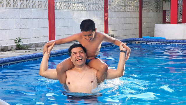 Divorced single dad and his 11-year-old Latino son play in the pool and teach him to swim during their vacation
