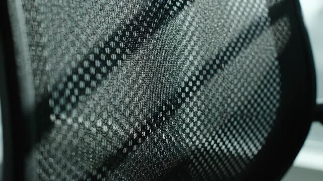 Close-up of black mesh office chair with pattern. Abstract modern mesh pattern design.