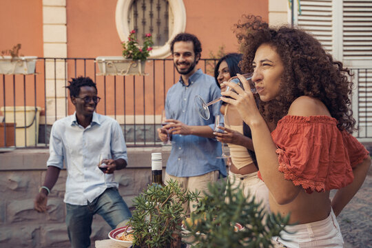 Young woman drinking red wine with friends during outdoor dinner