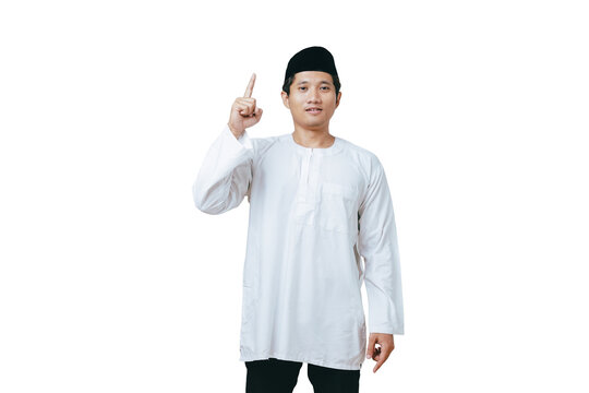 Young Muslim man in white baju kurung and black peci pointing one index finger upward against white background