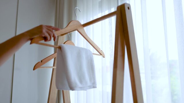 Person Hanging White Garments on Wooden Hangers in Minimalist Bedroom