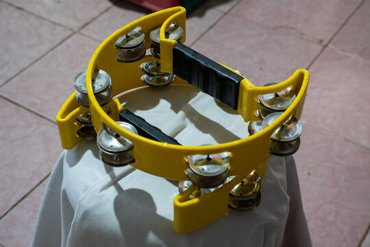 Yellow tambourine standing upright on a draped white fabric