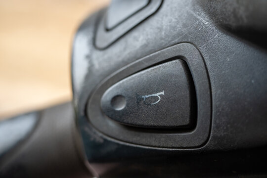 Close up of a black plastic motorcycle horn button