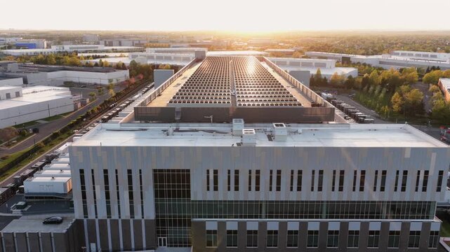 Aerial establishing shot of modern data center in Ashburn Virginia at sunset, with expansive rooftop infrastructure and industrial buildings supporting cloud computing and digital networks
