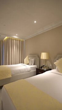 Entering a clean, modern hotel room featuring two single beds with white linens, yellow runners, and drawn curtains. Perfect for travel concepts.
