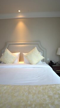 Close-up view of a large, comfortable hotel bed featuring crisp white sheets, an elegant yellow pillow, and a patterned bed runner.