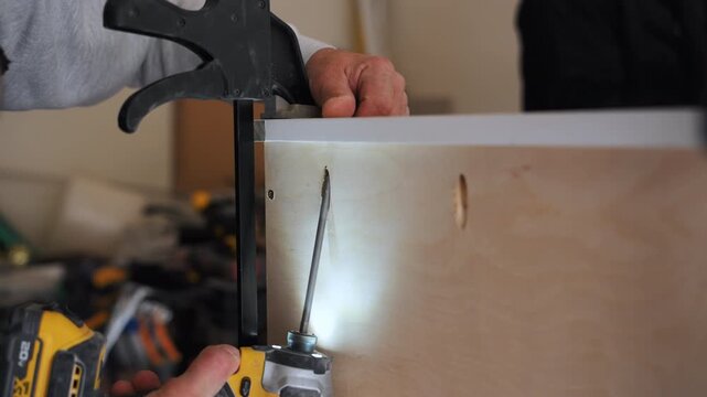 Furniture assembly process showing fastening components during kitchen or cabinet installation in home renovation. Close up