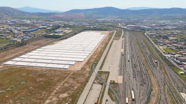 High-angle aerial footage displaying the thriasio pedio freight terminal, a major logistics and railway hub in aspropyrgos, greece, with numerous tracks and parked cargo trains