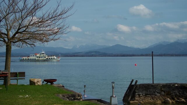 Passenger ferry crossing the blue water of Chiemsee near Fraueninsel on a sunny spring day.