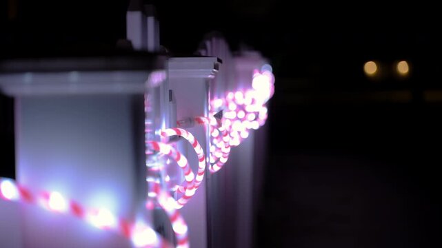 Person reaching out and touching colorful string lights at night. Close up of hand interacting with glowing outdoor decorative lights.