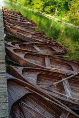 Fototapeta premium Wooden boats at a scenic lake pier. Calm forest lake with wooden boats. Travel destination in Plitvice Lake. Boat on clear water. Tourism and outdoor recreation. Peaceful lakeside vacation.