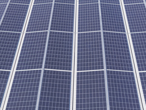 Aerial view of solar panels arranged in a geometric grid pattern reflecting the bright daylight in Taiwan.