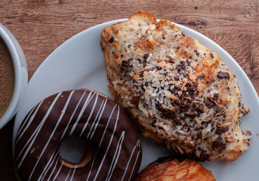 Reposteria fina, pan dulce mexicano para desayuno postres o cenas en familia, tradicional. Vista cenital de dona de chocolate y hojaldre cubierto con chocolate y coco, en mesa de madera.