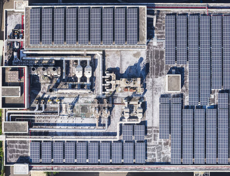 Aerial view of solar panels and industrial piping systems on a factory rooftop under bright sunlight Taiwan.
