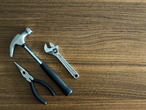 Hammer Pliers and Adjustable Wrench Flat Lay on Wooden Table DIY Repair Tools Home Improvement Construction Workshop Maintenance Hardware Background
