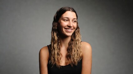 Naklejka premium Woman laughing and seated in simple studio background