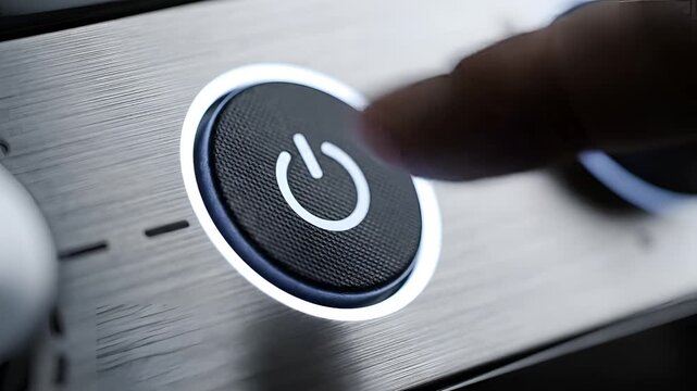 Close up of a finger pressing a glowing power button on a modern appliance.