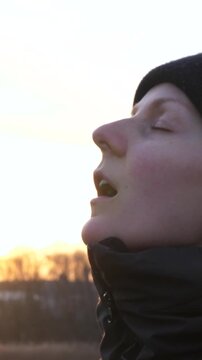 Hopeful woman taking off her surgical mask and breathing fresh air, symbolizing the end of the pandemic, newfound freedom, and a return to normalcy with the warm sunset light in the background