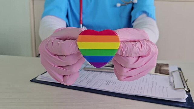 Health worker shows rainbow heart symbol during patient care at clinic in 2023