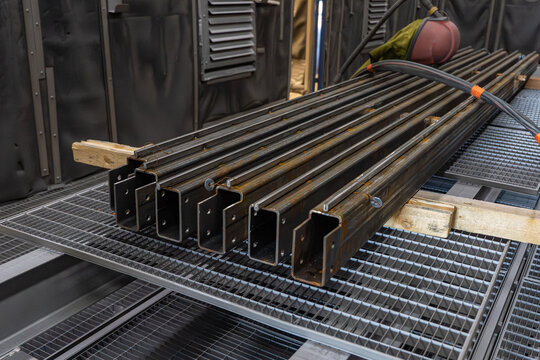 Alignement de profil&eacute;s m&eacute;talliques en acier sur cales en bois dans un atelier de fabrication pour la pr&eacute;paration de charpentes industrielles.