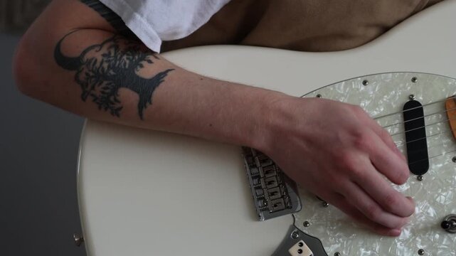 A person is using a pick to strum the strings of an electric guitar.
