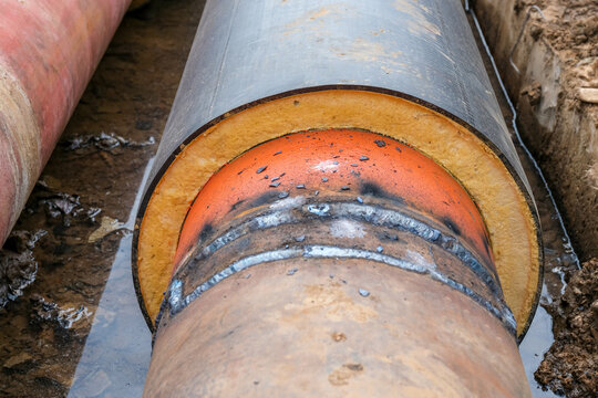 Close up of welded joint on pre insulated heating pipe with visible foam insulation and steel connection in trench