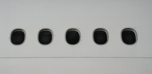 Three commercial airplane windows in a row on white fuselage exterior side profile of passenger aircraft windows from outside view for aviation and travel photography themes © Aryanto