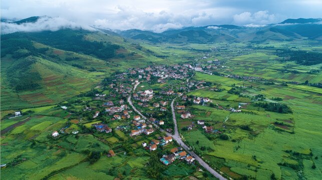 Aerial View of a Serene Rural Landscape Surrounded by Lush Green Fields and Rolling Hills Under a Cloudy Sky with a Small Village
