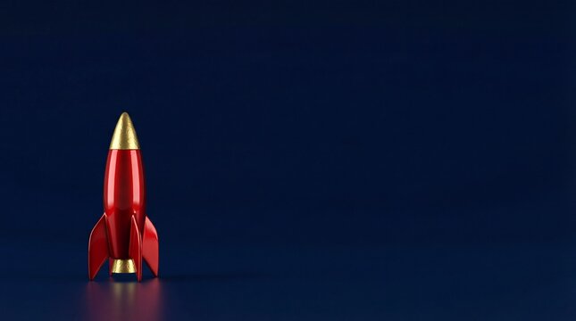 Red toy rocket ship with gold nose cone standing on dark blue background
